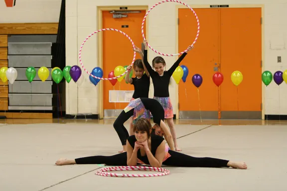 Gymnasts holding splits and hoops in a group shape.